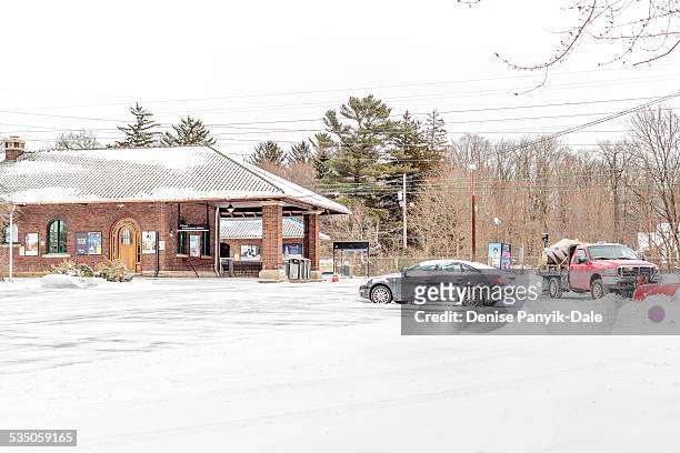 Normally full train station parking lot stands empty with exception of one car and a snowplow. New Jersey Transit cancelled train service in...