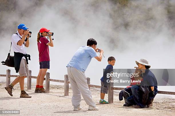 New Zealand North Island, Rotorua area Wai-O-Tapu . Visiting tourists, a mixture of white and Asian families, enveloped by the steam from the thermal...