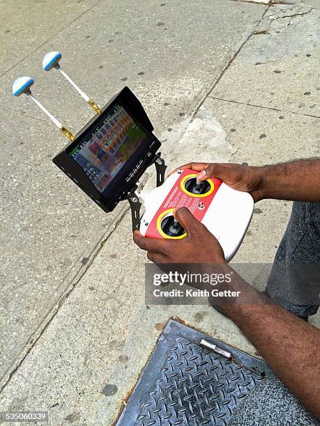 Close-Up of a Drone Pilot's Hands on the Remote Control System as He Flies a Drone While Sitting on a Sidewalk in Fort Greene Brooklyn NYC; the...