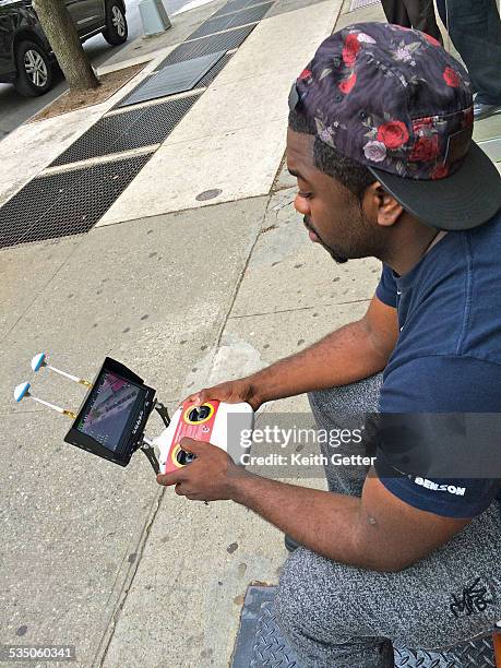 Drone Pilot Working the Remote Control System as He Looks Down at the Remote Controller and Screen while sitting on a Bench on a Sidewalk in Ft,...