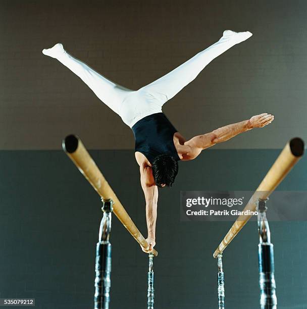 gymnast performing routine on parallel bars - gymnaste photos et images de collection