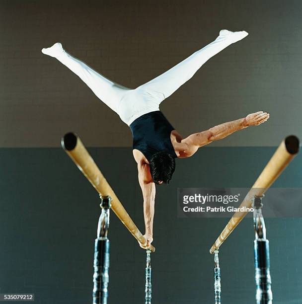 gymnast performing routine on parallel bars - male gymnast stock pictures, royalty-free photos & images