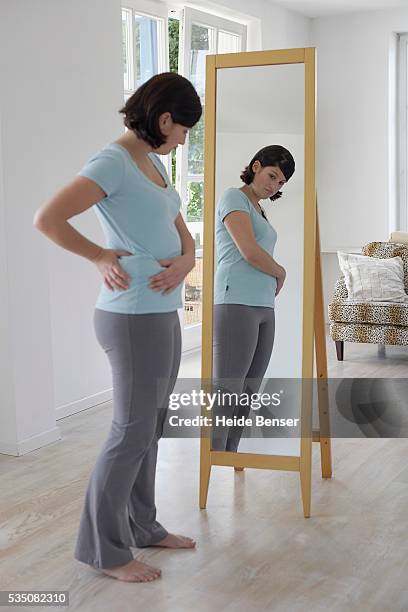 woman looking at her body in the mirror - woman-looking-into-mirror-full-body stock pictures, royalty-free photos & images