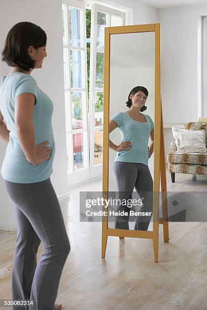 woman looking at herself in the mirror - full length mirror stock-fotos und bilder