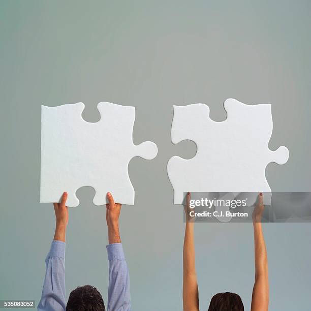 man and woman carrying jigsaw puzzle pieces - puzzleteile stock-fotos und bilder