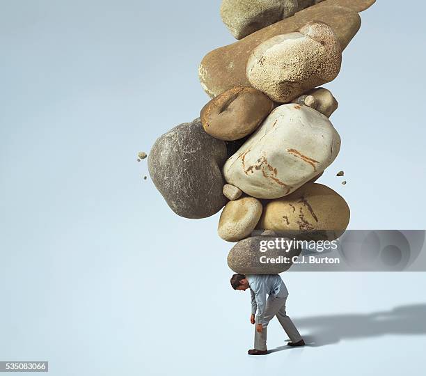 man carrying large rocks on his back - back pain man stock pictures, royalty-free photos & images