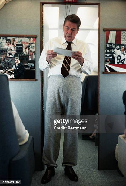 Air Force One: Full length view of President Ronald Reagan in sweat pants and a tie reading in a doorway.