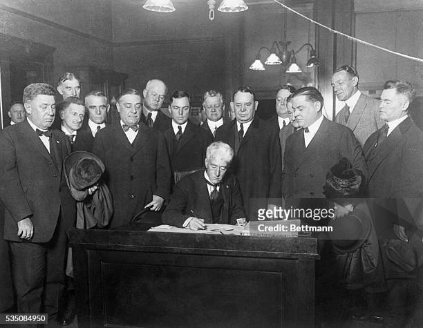 Judge Landis signs the contract as baseball commissioner. Left to right: Phil Ball, St. Louis Browns; Barney Dreyfus, Pirate; Connie Mack, Athletics;...