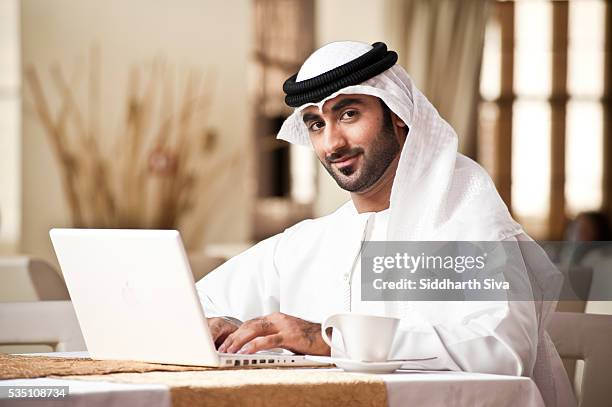 arab man working on a laptop. - emirati laptop stock pictures, royalty-free photos & images