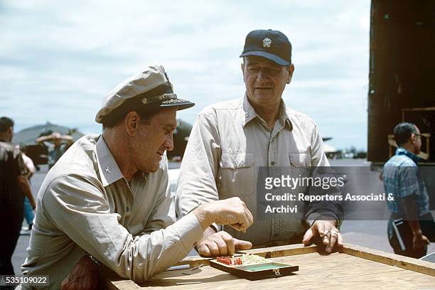 American actors Kirk Douglas and John Wayne playing chess on the set of In Harm's Way. USA, 1965