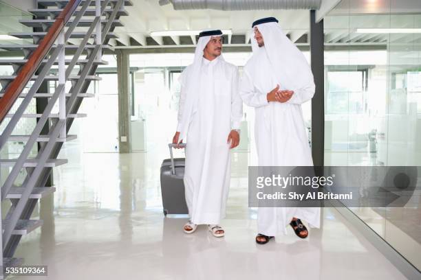 two arab men walking with suitcase in office. - djellaba stockfoto's en -beelden