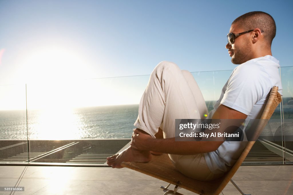 Man wearing sunglasses sitting on chair.
