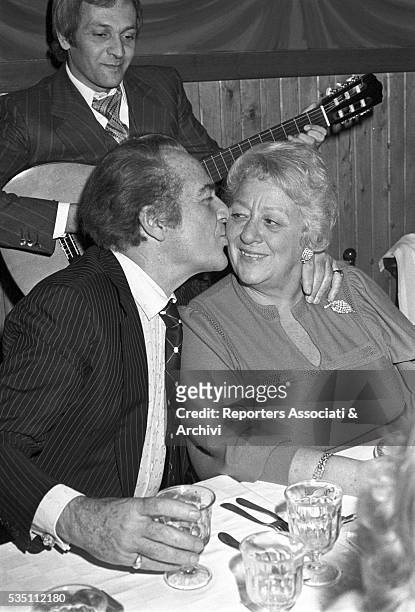 Italian actor Rossano Brazzi kissing his wife Lidia Bertolini during a dinner after a cinema premiere. 1977