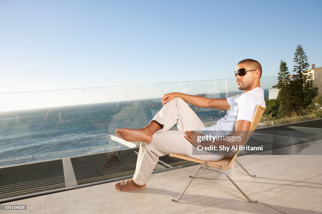 Man wearing sunglasses sitting on chair.