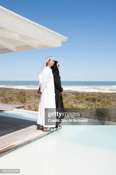 arab couple standing on poolside. - arab villa stock-fotos und bilder