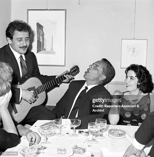 Italian actor Rossano Brazzi - beside Argentinian actress Linda Cristal - singing accompanied by Italian singer-songwriter Domenico Modugno at the...