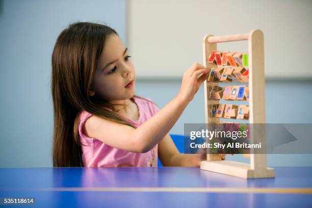a small girl playing with an abacus inside a classroom. - abaco fotografías e imágenes de stock