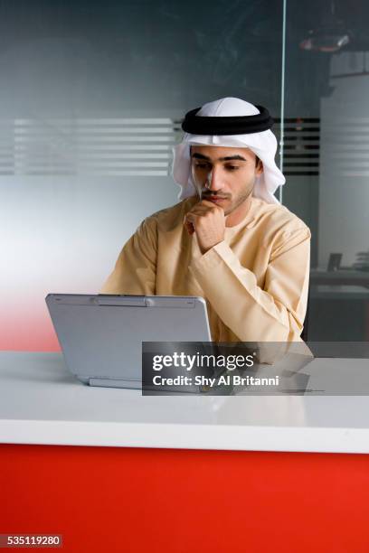 an emirati man working on a laptop. - emirati guy using laptop stock-fotos und bilder