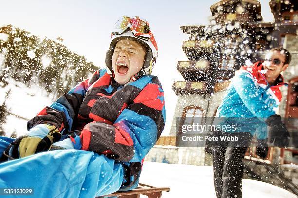 boy sat on toboggan being hit with a snowball - bourg saint maurice fotografías e imágenes de stock