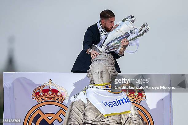 Captain Sergio Ramos of Real Madrid kisses the trophy as he touches Cibeles statue head as he celebrate with his team and fans at Cibeles square...