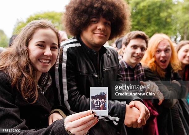 An American guest from Bellingham shows a polaroid group picture while waiting for Alabama Shakes's performance onstage at Deer Lake Park Festival...