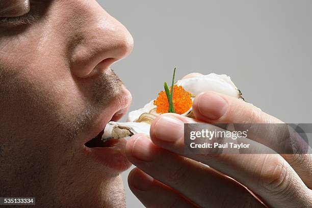 man eating raw oyster in the shell - afrodisíaco fotografías e imágenes de stock