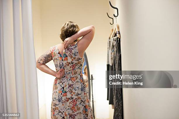 young woman trying on dress in changing room - dressing room fotografías e imágenes de stock