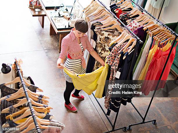 young female customer shopping for dress - tienda de ropa fotografías e imágenes de stock
