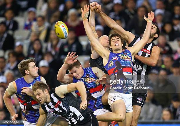 Josh Dunkley of the Bulldogs and Brodie Grundy of the Magpies and Ben Reid of the Magpies compete for the ball during the round 10 AFL match between...