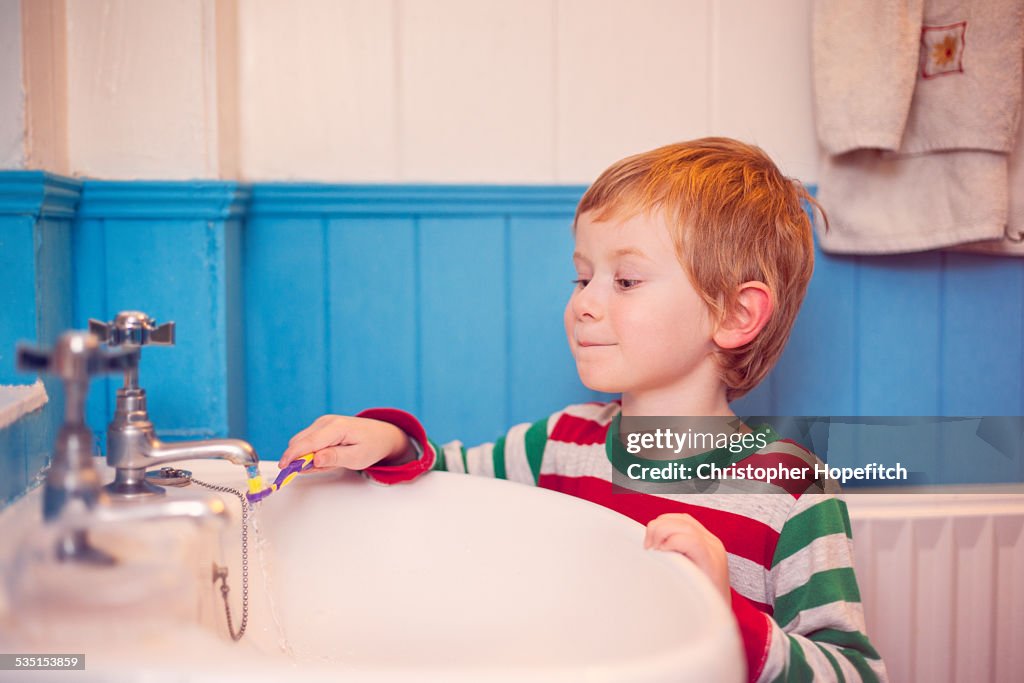 Young boy rinsing his toothbrush