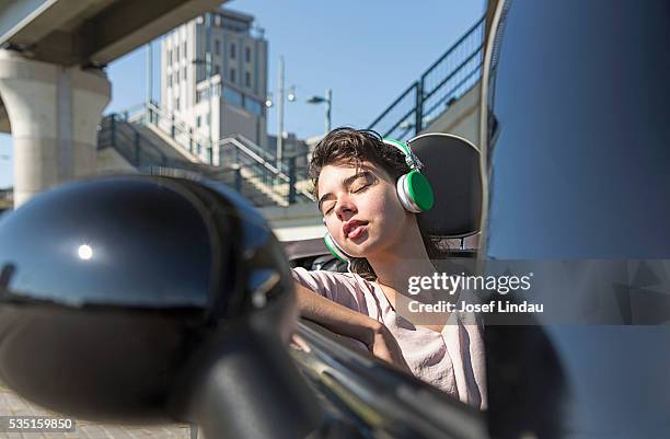 woman sleeping and listening to music in open top car - josef lindau stock-fotos und bilder