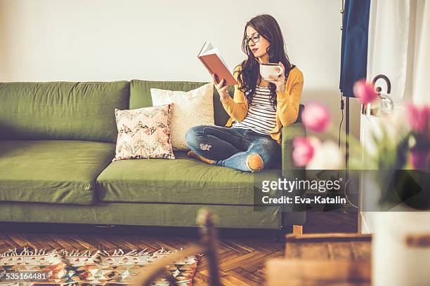 young woman reading a book at home - coffee read stock pictures, royalty-free photos & images