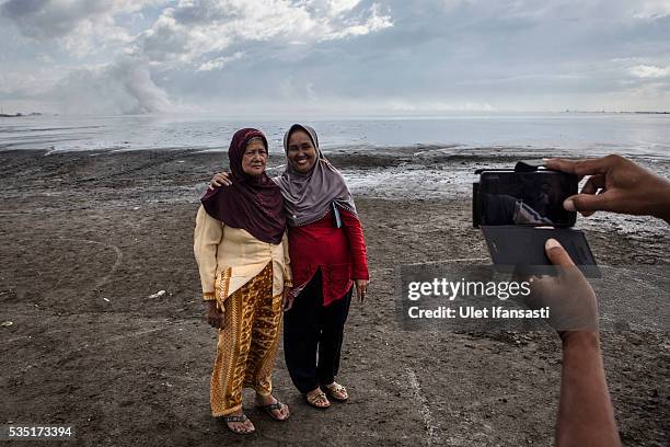 Visitors poses for photograph as watching smoke coming out from the mudflow during the tenth anniversary of the mudflow eruption on May 29, 2016 in...