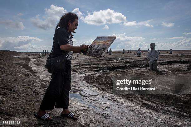 An artist using mud to paints as they take action paint together at mudflow during the tenth anniversary of the mudflow eruption on May 29, 2016 in...