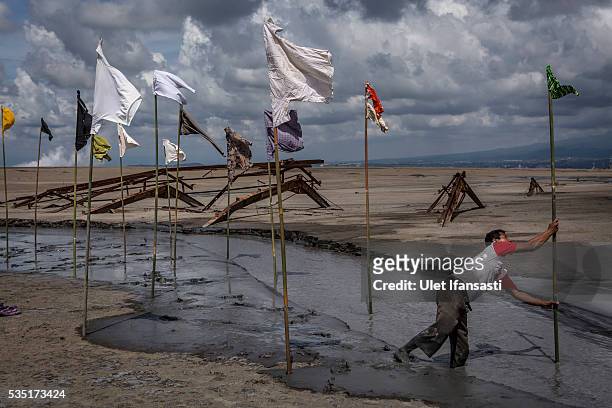Man sets up an art installation by artist Dadang Christanto, with title 'Gombal' known as rags at mudflow during the tenth anniversary of the mudflow...