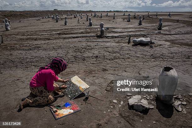 An artist, Novi, paints at mudflow during the tenth anniversary of the mudflow eruption on May 29, 2016 in Sidoarjo, East Java, Indonesia. On 29 May...