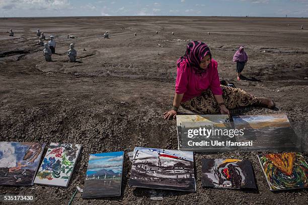 An artist, Novi, holds her painting at mudflow during the tenth anniversary of the mudflow eruption on May 29, 2016 in Sidoarjo, East Java,...