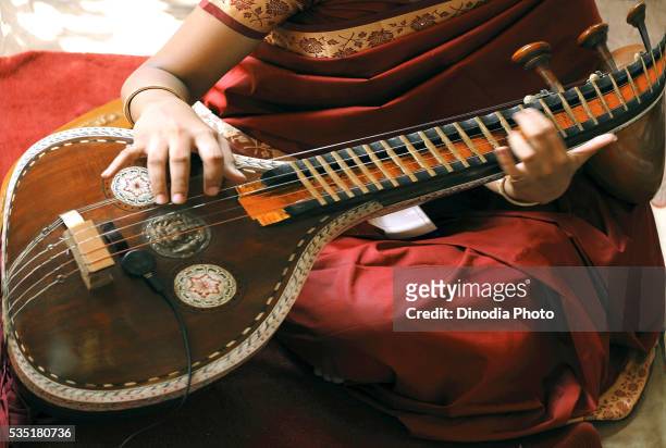 young woman playing a south indian musical instrument called a veena during a religious ceremony. - sitar stockfoto's en -beelden