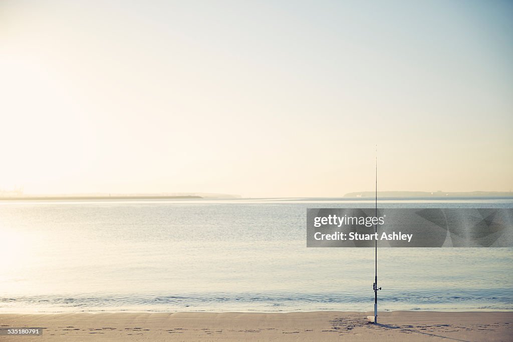 Sunrise fishing and fishing rod on beach