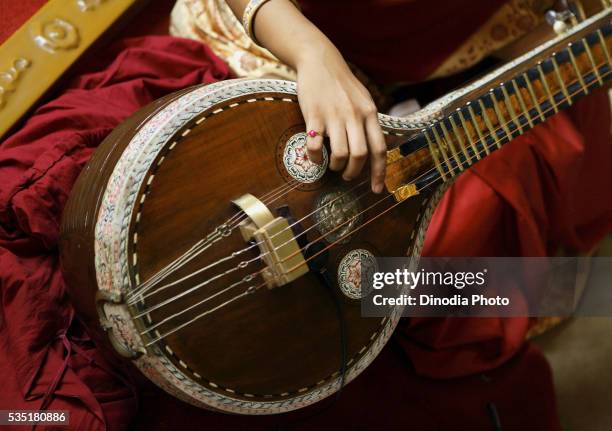 young woman playing a south indian musical instrument called a veena during a religious ceremony. - musical instrument stock pictures, royalty-free photos & images