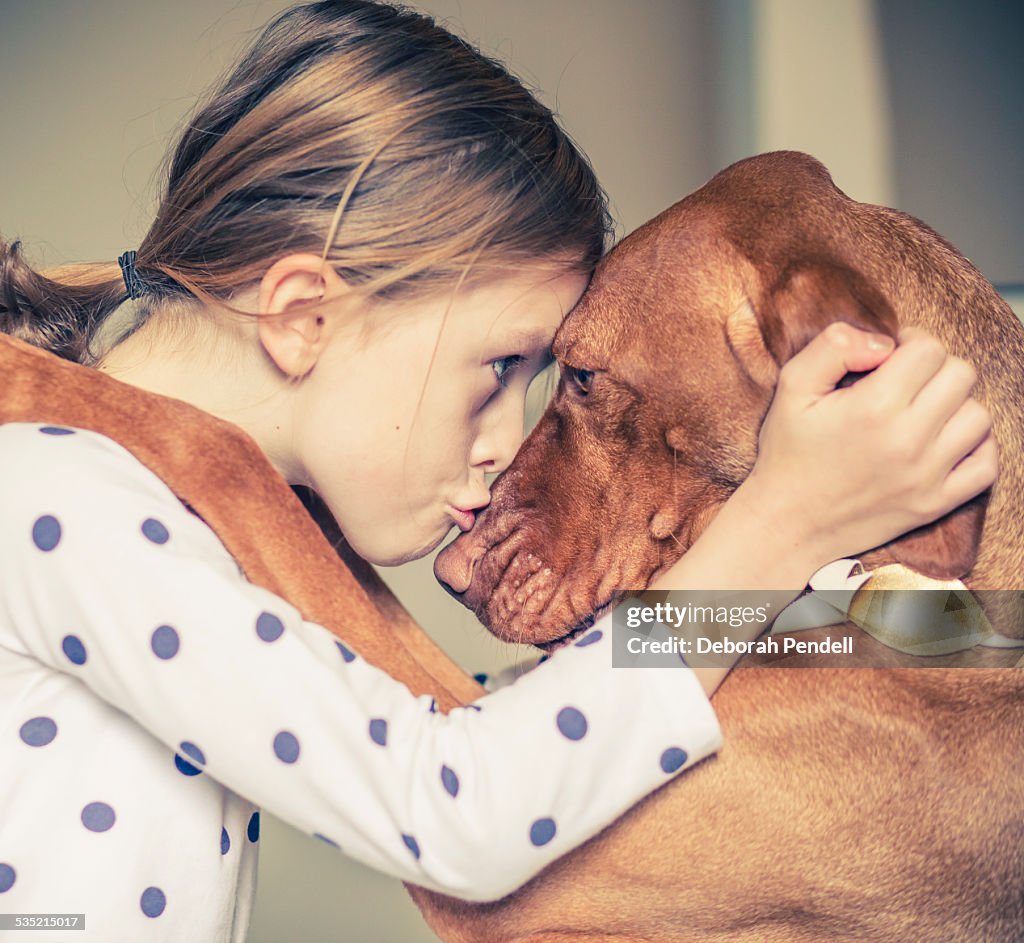 A hug between a young girl and her pet dog