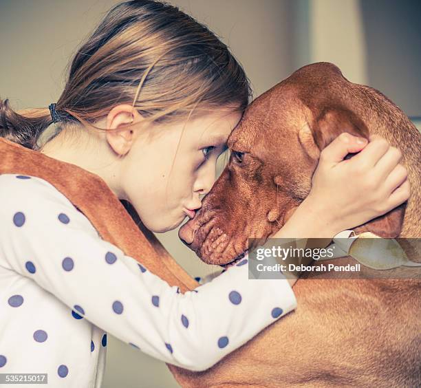 a hug between a young girl and her pet dog - dog kiss stock pictures, royalty-free photos & images