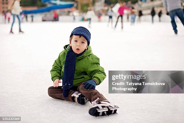 little boy ice-skating in outdoor rink - learning to ice skate stock pictures, royalty-free photos & images