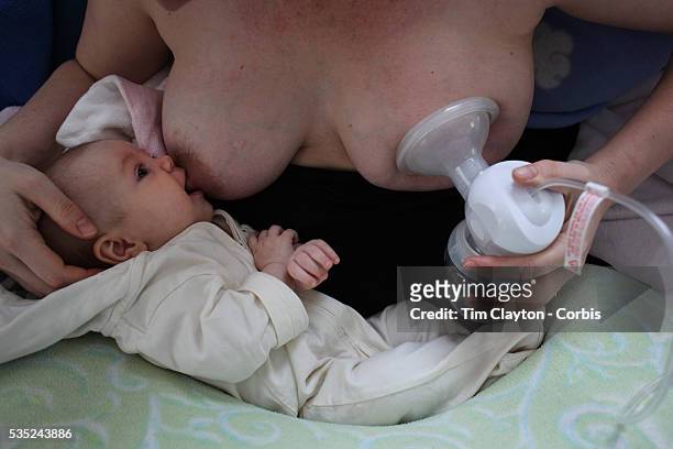 Two month old baby girl baby breast feeding as her mother uses a milk pump to express milk into a container on her other breast. Photo Tim Clayton