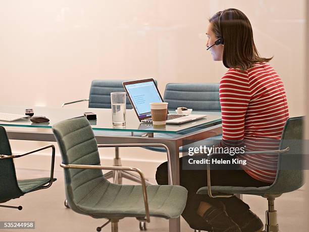 young woman with headset working on laptop - archival office stock pictures, royalty-free photos & images