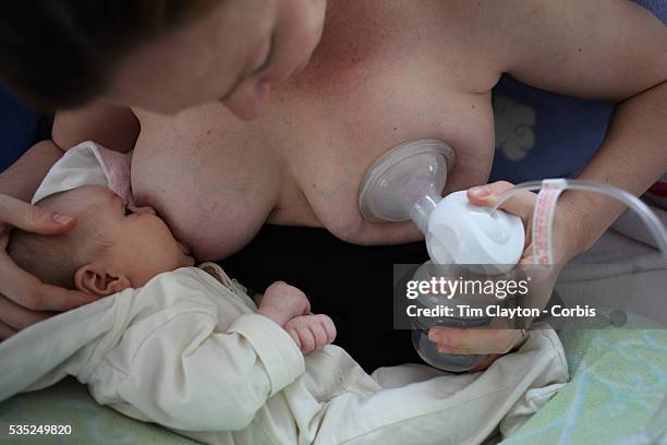 Two month old baby girl baby breast feeding as her mother uses a milk pump to express milk into a container on her other breast. Photo Tim Clayton