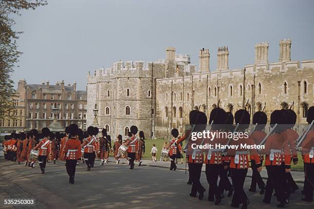 The Queen's Guard marching on Thames Street at the front of Windsor Castle, Berkshire, England, circa 1960.