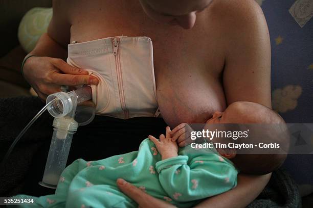 Two month old baby girl baby breast feeding as her mother uses a milk pump to express milk into a container on her other breast. Photo Tim Clayton