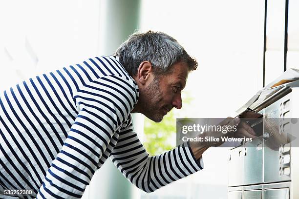 content middle-aged man looking into mailbox - mailbox foto e immagini stock