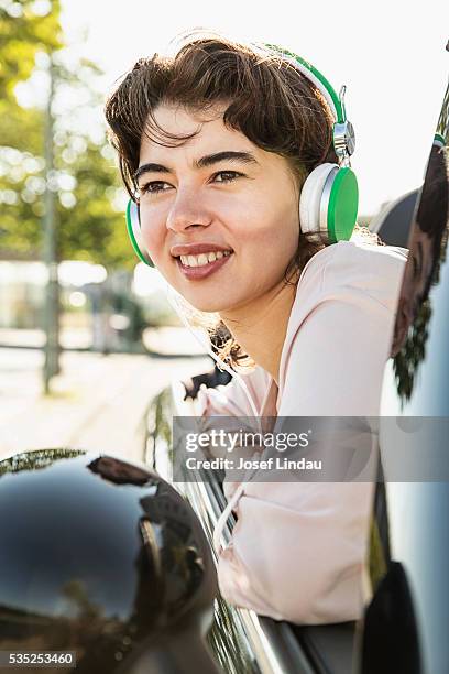 confident woman listening to music in open top car - josef lindau stock-fotos und bilder